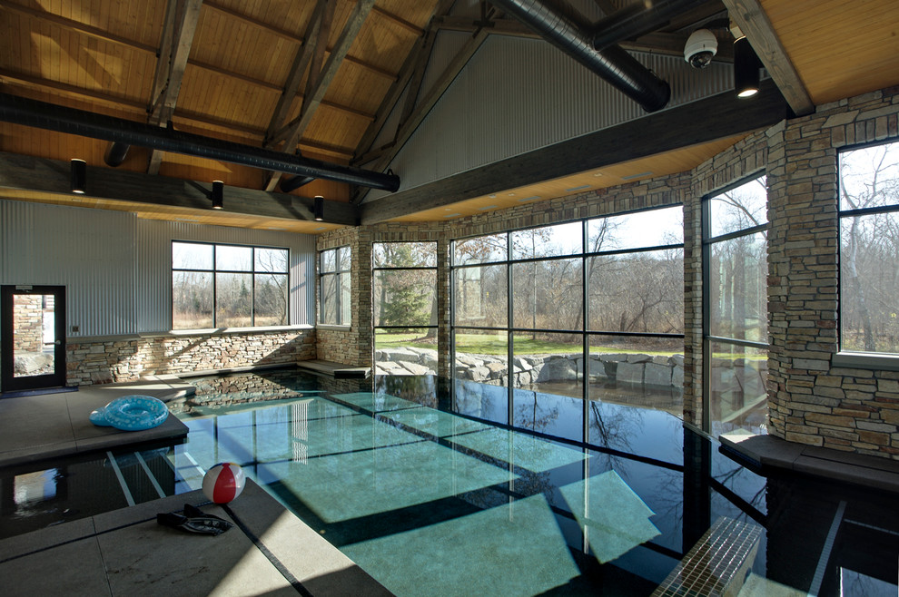 This is an example of a contemporary indoor custom-shaped pool in Minneapolis with concrete pavers.