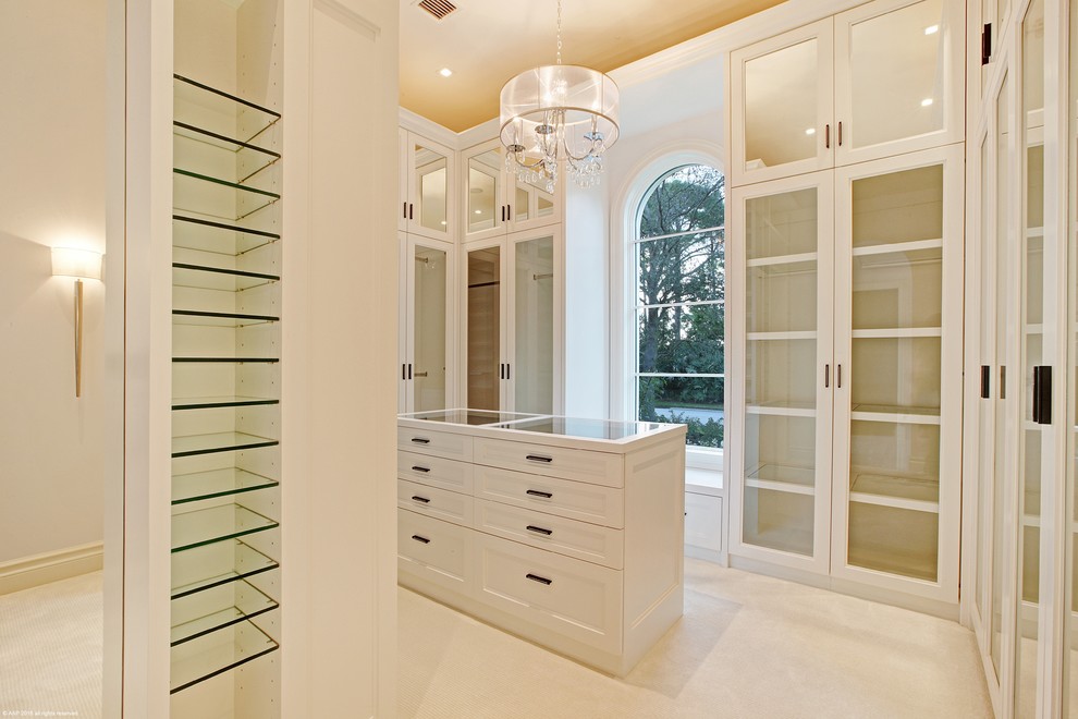 Photo of a mid-sized traditional gender-neutral walk-in wardrobe in Miami with carpet, glass-front cabinets and white cabinets.