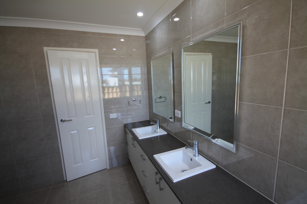 Photo of a contemporary bathroom in Perth with flat-panel cabinets, white cabinets, a drop-in tub, gray tile, a drop-in sink, a corner shower and a one-piece toilet.