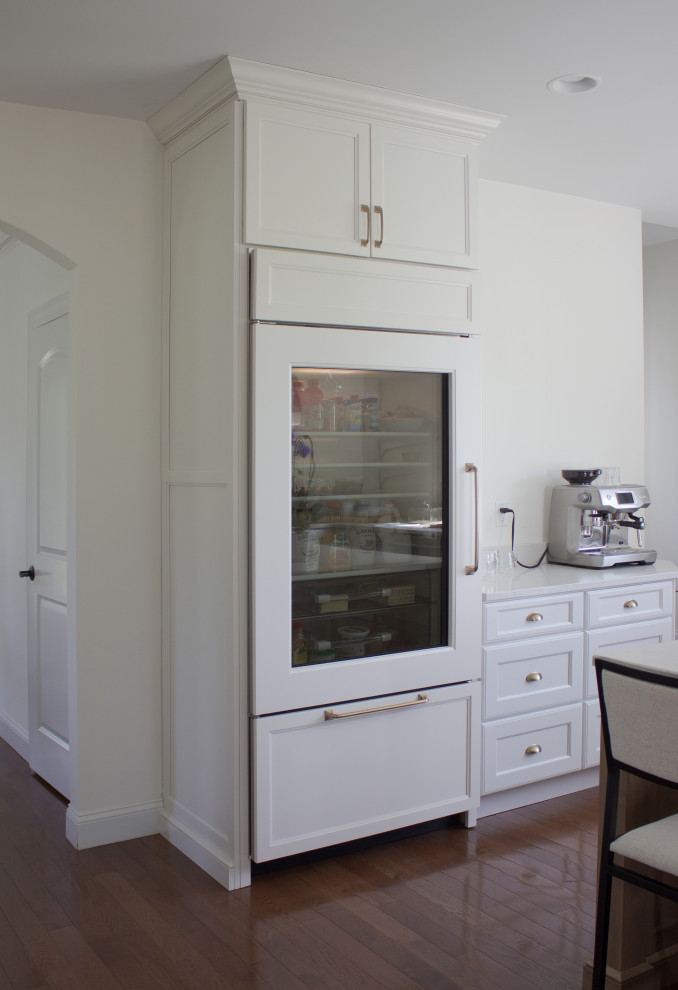 Kitchen - large transitional u-shaped medium tone wood floor and brown floor kitchen idea in New York with a farmhouse sink, recessed-panel cabinets, white cabinets, quartz countertops, stainless steel appliances, an island and white countertops