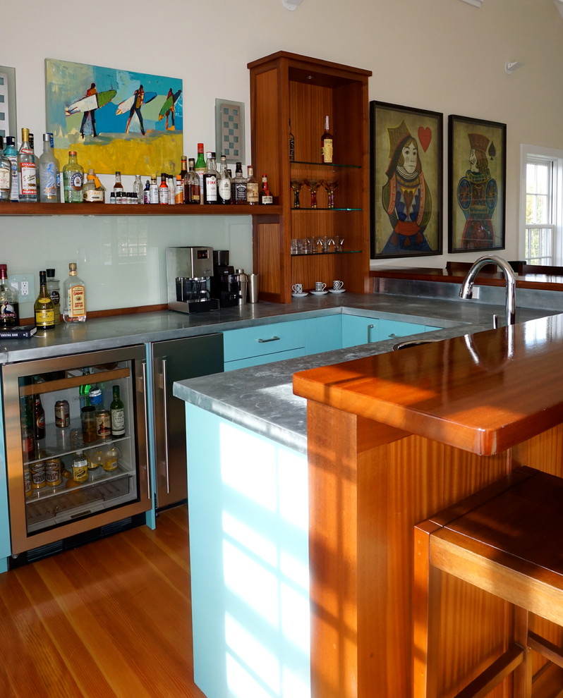 Photo of a contemporary home bar in Boston with flat-panel cabinets, blue cabinets, zinc benchtops, glass sheet splashback and light hardwood floors.