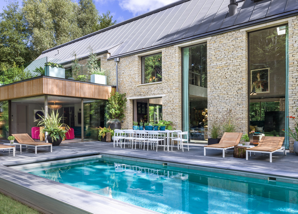 Photo of a mid-sized contemporary backyard rectangular pool in London with decking.