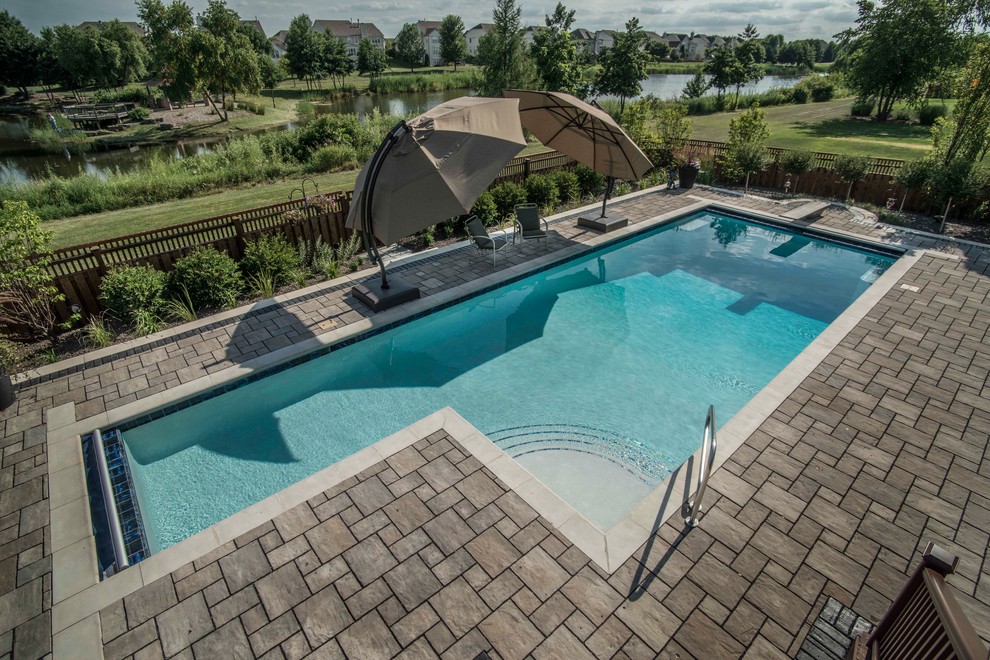 This is an example of a mid-sized traditional backyard l-shaped lap pool in Chicago with concrete pavers.