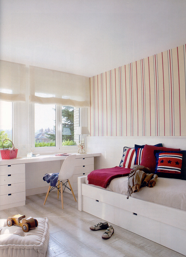 This is an example of a mid-sized beach style gender-neutral kids' bedroom for kids 4-10 years old in Madrid with multi-coloured walls and painted wood floors.