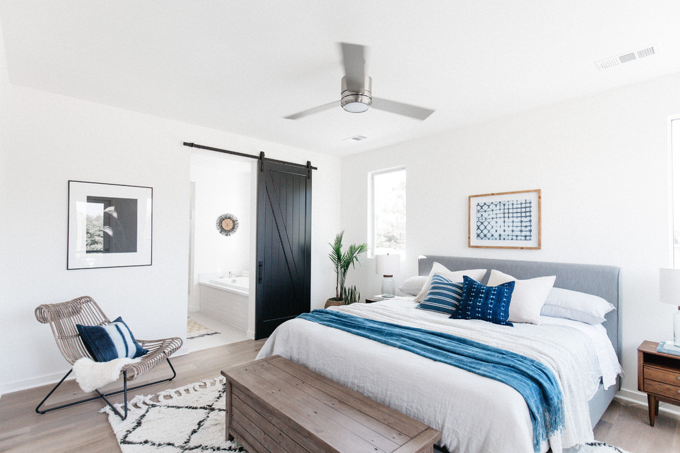 This is an example of a beach style bedroom in Los Angeles with white walls, dark hardwood floors and brown floor.