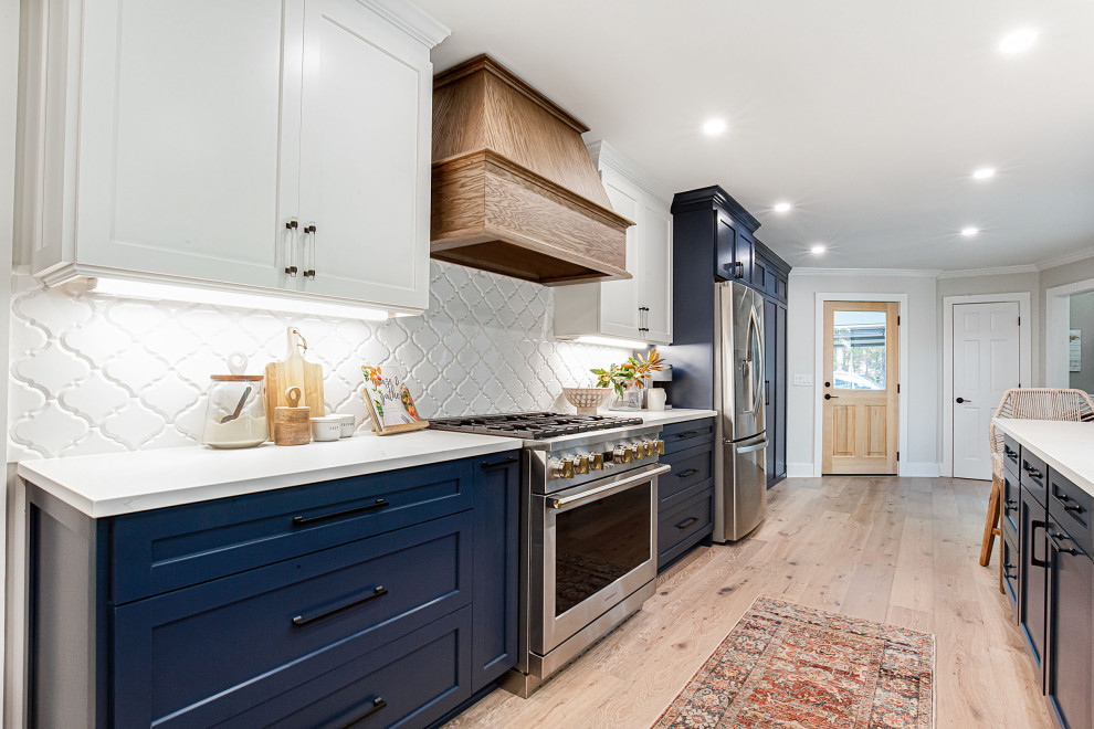 Example of a mid-sized farmhouse galley brown floor eat-in kitchen design in Atlanta with an undermount sink, shaker cabinets, blue cabinets, quartz countertops, white backsplash, mosaic tile backsplash and stainless steel appliances