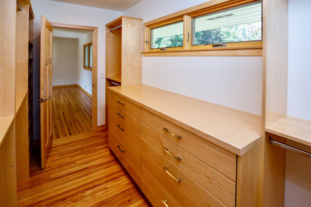 Large walk-in wardrobe in Minneapolis with flat-panel cabinets and light hardwood floors.