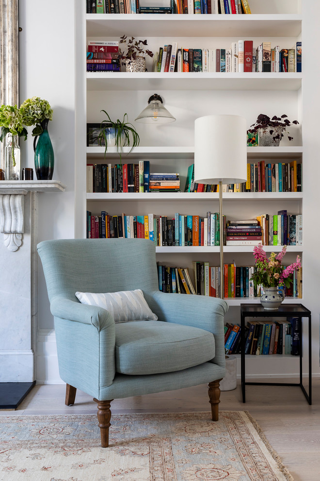 This is an example of a transitional open concept living room in London with a library and grey walls.