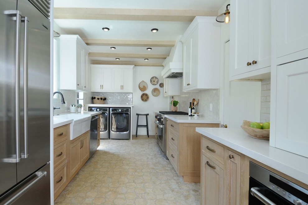 Photo of a mid-sized mediterranean galley separate kitchen in Los Angeles with a farmhouse sink, shaker cabinets, beige cabinets, quartz benchtops, mosaic tile splashback, stainless steel appliances, brick floors, no island, beige floor and white splashback.