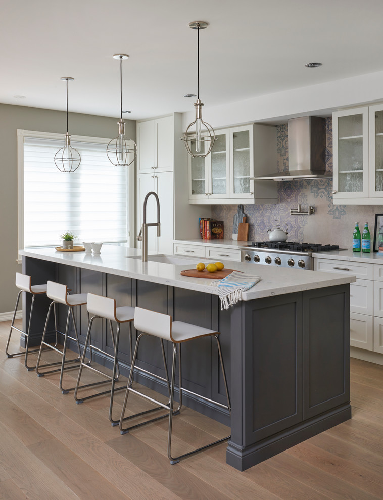 This is an example of a transitional kitchen in Toronto with an undermount sink, shaker cabinets, white cabinets, stainless steel appliances, medium hardwood floors and with island.
