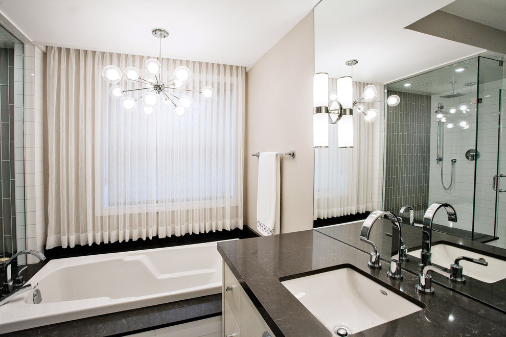 Large modern master bathroom in Toronto with an undermount sink, flat-panel cabinets, light wood cabinets, engineered quartz benchtops, a drop-in tub, a corner shower, a one-piece toilet, gray tile, porcelain tile, beige walls and porcelain floors.
