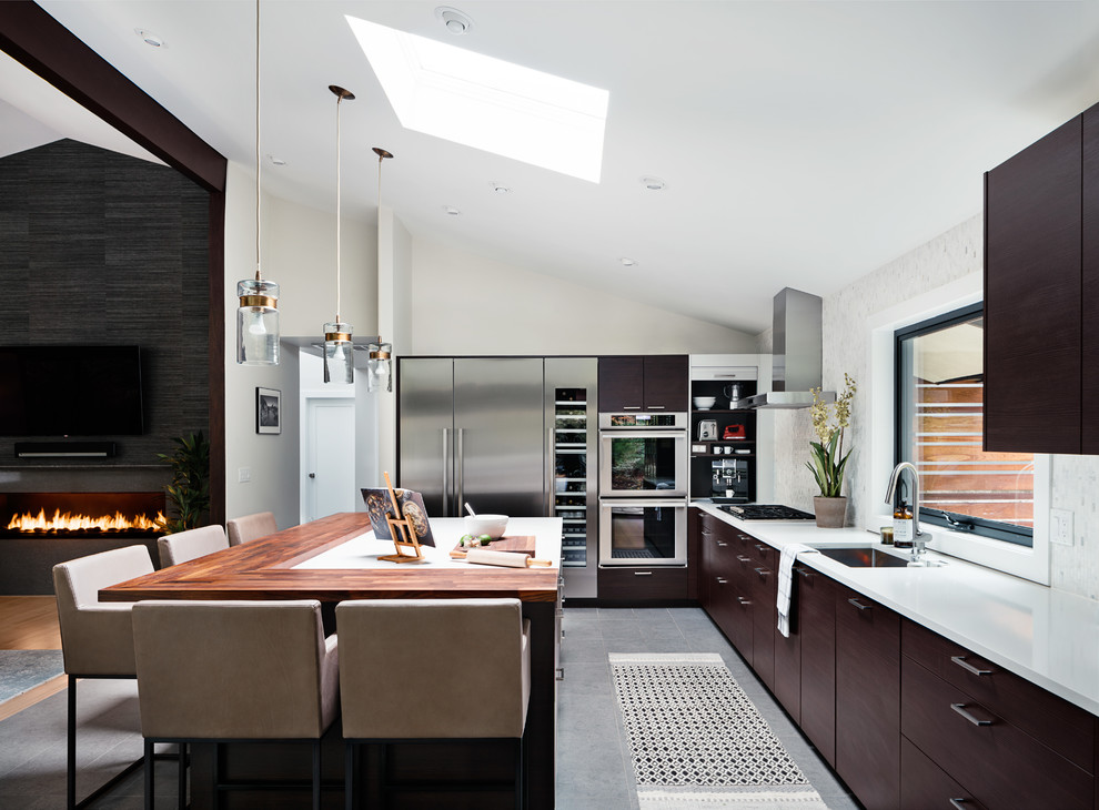 Inspiration for a large midcentury l-shaped open plan kitchen in New York with flat-panel cabinets, dark wood cabinets, with island, an undermount sink, stainless steel appliances, grey floor and white benchtop.