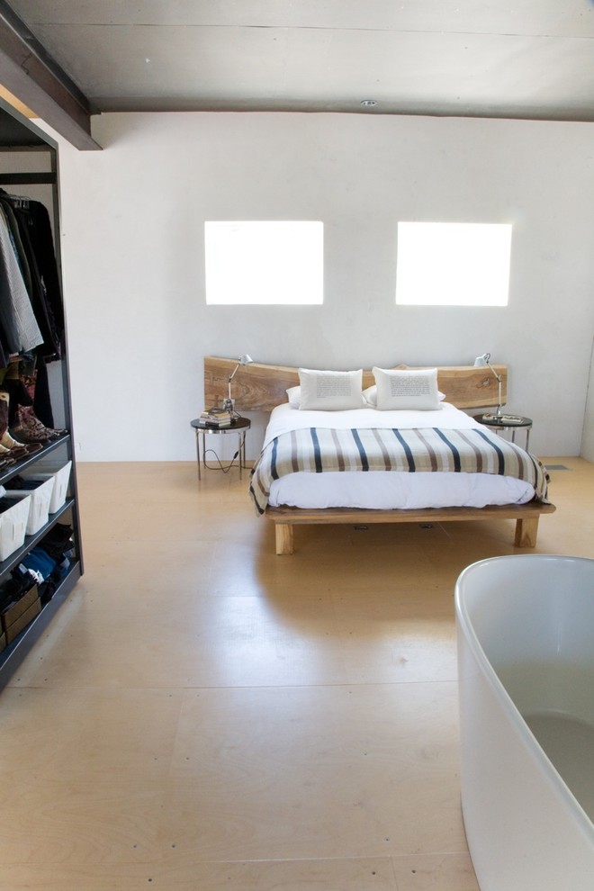 This is an example of a scandinavian bedroom in Austin with white walls, light hardwood floors and no fireplace.