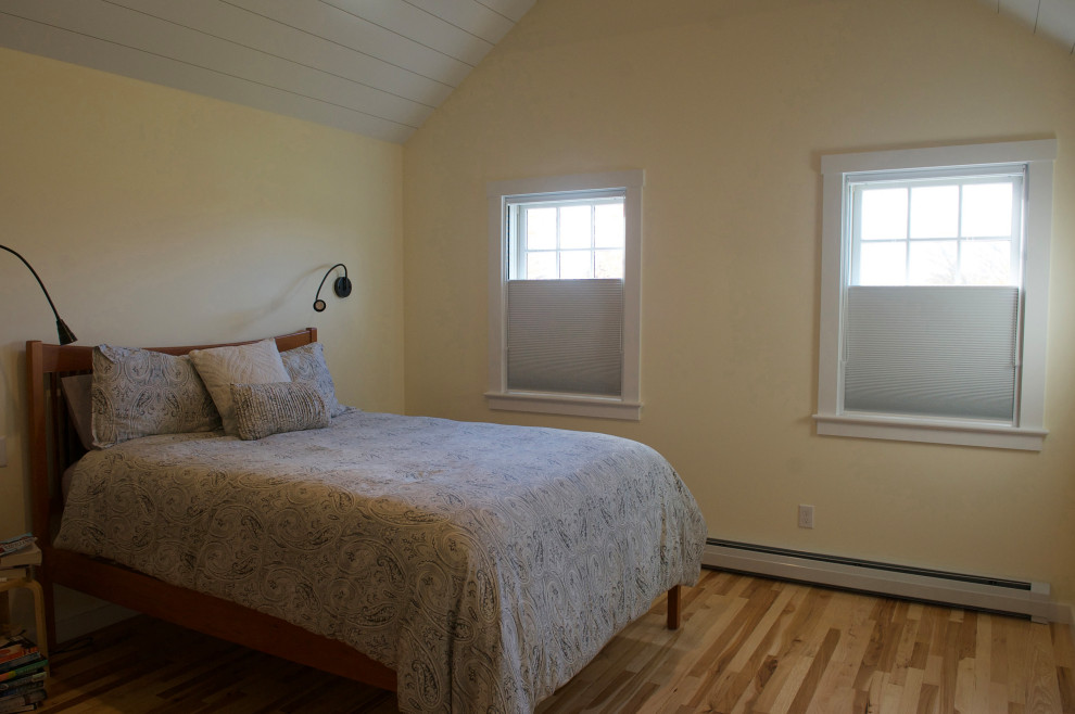 Idee per una camera matrimoniale country di medie dimensioni con pareti gialle, pavimento in legno massello medio, pavimento marrone e travi a vista