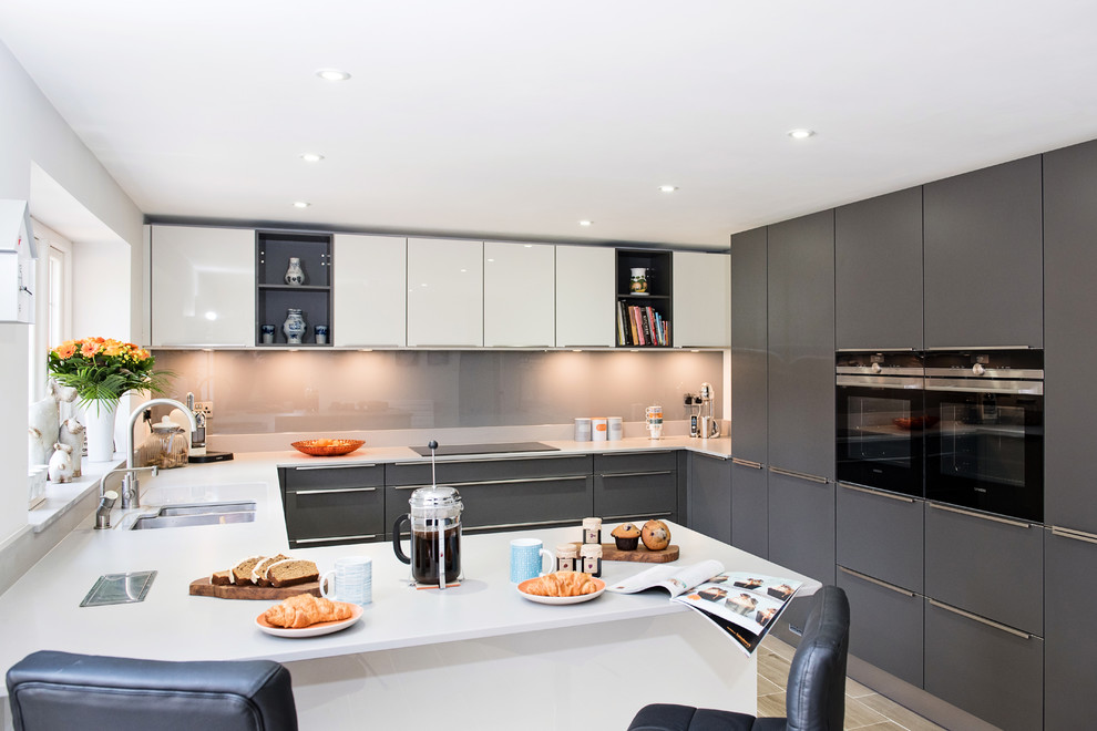 Inspiration for a mid-sized contemporary u-shaped open plan kitchen in Surrey with grey cabinets, stainless steel appliances, a peninsula, a double-bowl sink, flat-panel cabinets, grey splashback and light hardwood floors.