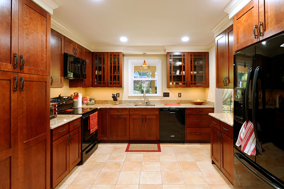 This is an example of a traditional l-shaped separate kitchen in DC Metro with a single-bowl sink, dark wood cabinets and black appliances.