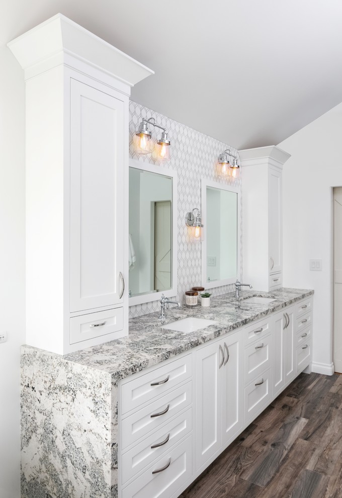 Large transitional master bathroom in Los Angeles with shaker cabinets, white cabinets, a freestanding tub, a corner shower, a one-piece toilet, white tile, marble, grey walls, vinyl floors, an undermount sink, granite benchtops, brown floor, a hinged shower door and multi-coloured benchtops.
