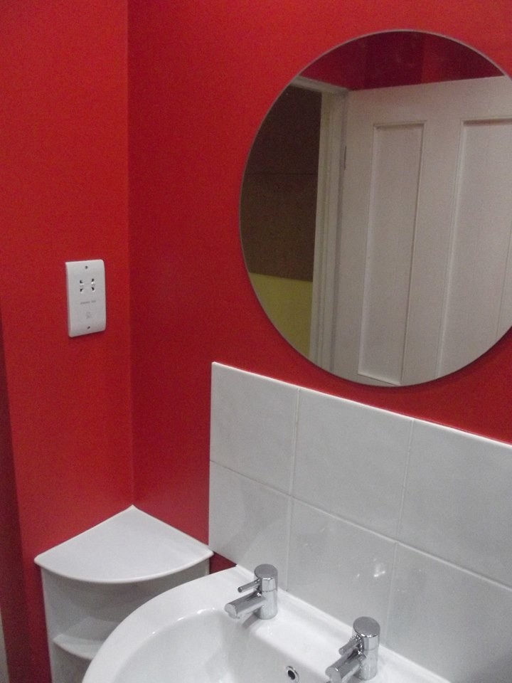 Photo of a small modern master bathroom with a pedestal sink, a double shower, white tile, cement tile, red walls and linoleum floors.