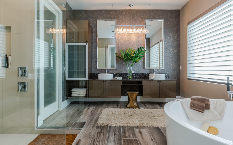 Design ideas for a contemporary master bathroom in Tampa with flat-panel cabinets, brown cabinets, a freestanding tub, an open shower, beige tile, brown walls, a vessel sink, brown floor, an open shower, black benchtops, wood-look tile, a double vanity and a floating vanity.