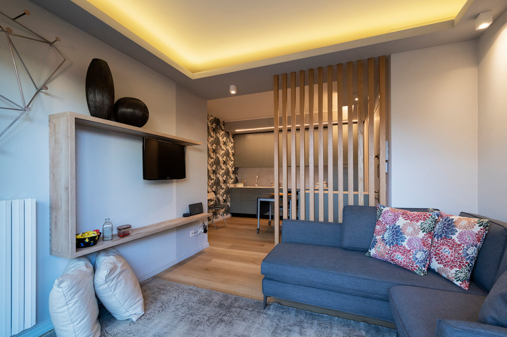 Foto de sala de estar abierta minimalista pequeña con paredes grises, suelo laminado, televisor colgado en la pared, suelo marrón, bandeja y alfombra