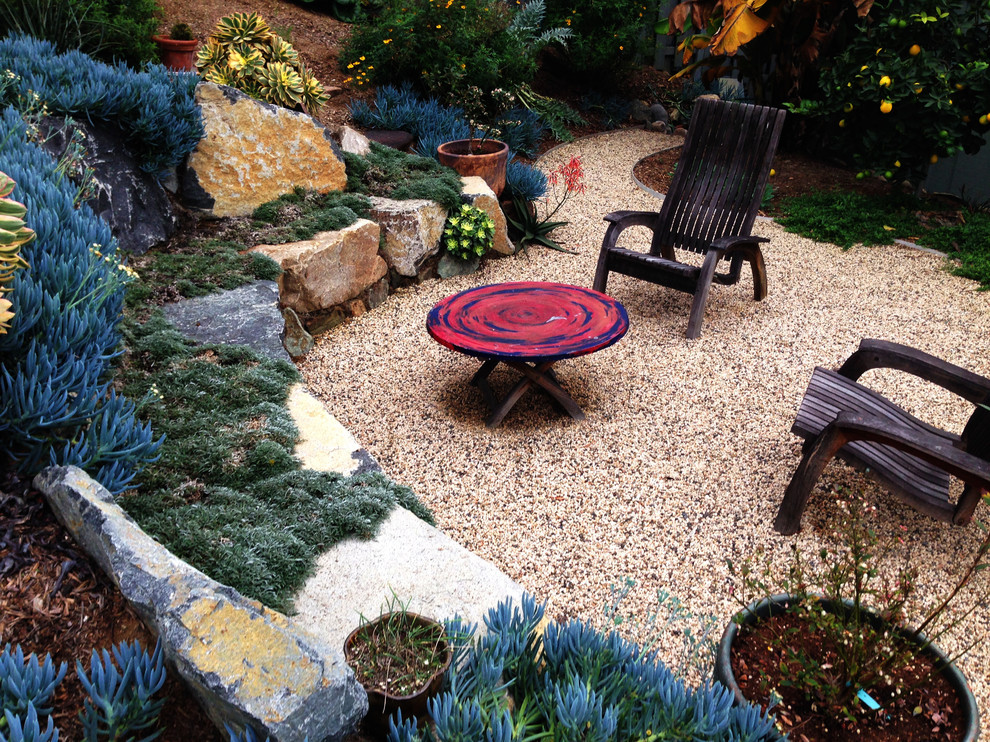 This is an example of a mid-sized country backyard full sun garden in San Diego with a retaining wall and gravel.