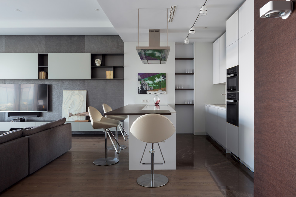 Design ideas for a contemporary open plan kitchen in Moscow with flat-panel cabinets, white cabinets, black appliances, a peninsula and brown floor.