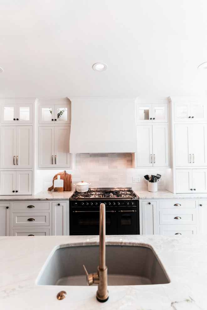 Example of a large transitional l-shaped light wood floor open concept kitchen design with an undermount sink, shaker cabinets, white cabinets, quartzite countertops, multicolored backsplash, porcelain backsplash, stainless steel appliances and an island