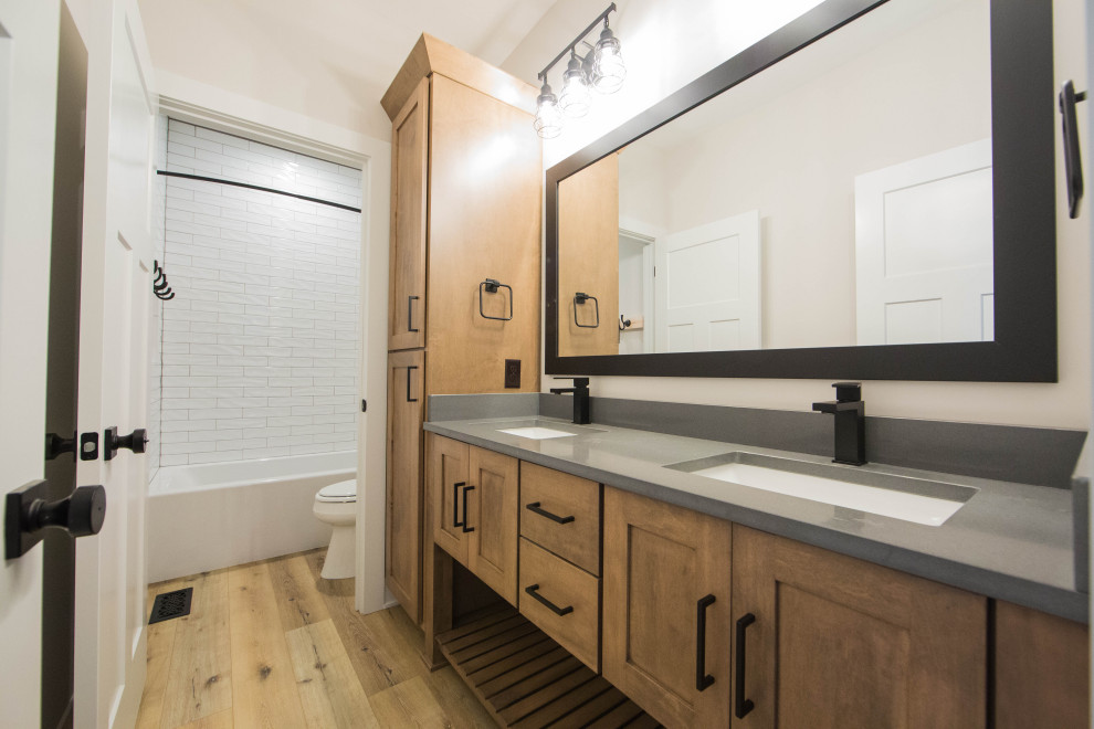 Mid-sized elegant 3/4 white tile and subway tile medium tone wood floor, brown floor and double-sink bathroom photo in Indianapolis with recessed-panel cabinets, brown cabinets, a two-piece toilet, white walls, an undermount sink, granite countertops, gray countertops and a freestanding vanity