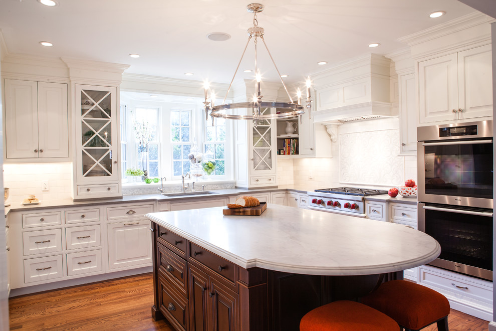 Inspiration for a traditional u-shaped kitchen in Newark with raised-panel cabinets, white cabinets, white splashback, subway tile splashback and stainless steel appliances.