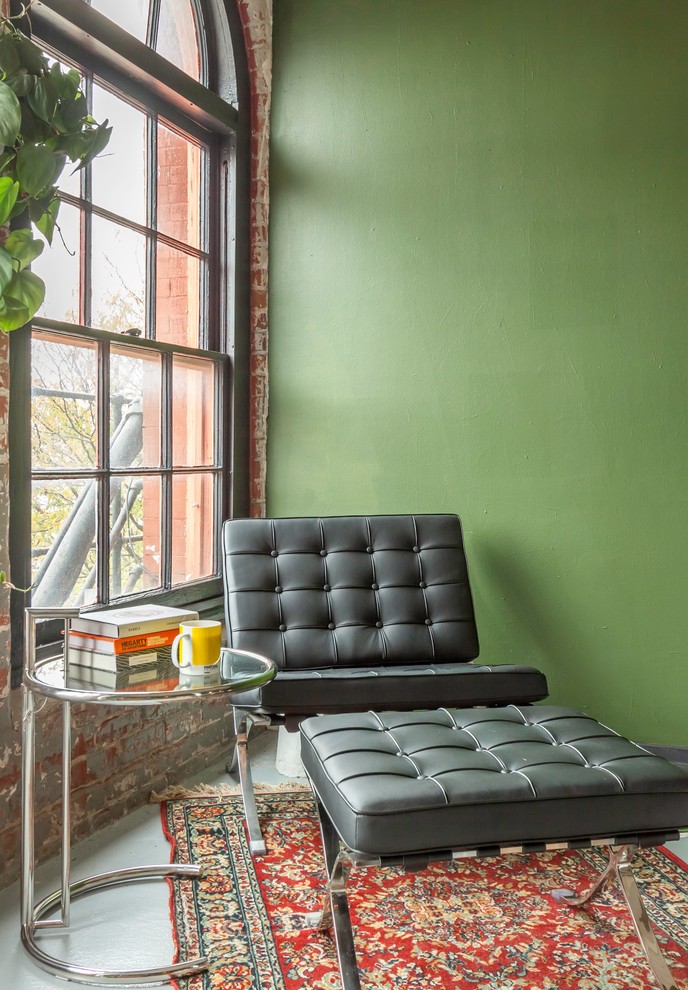 This is an example of a small contemporary loft-style living room in Omaha with green walls and concrete floors.
