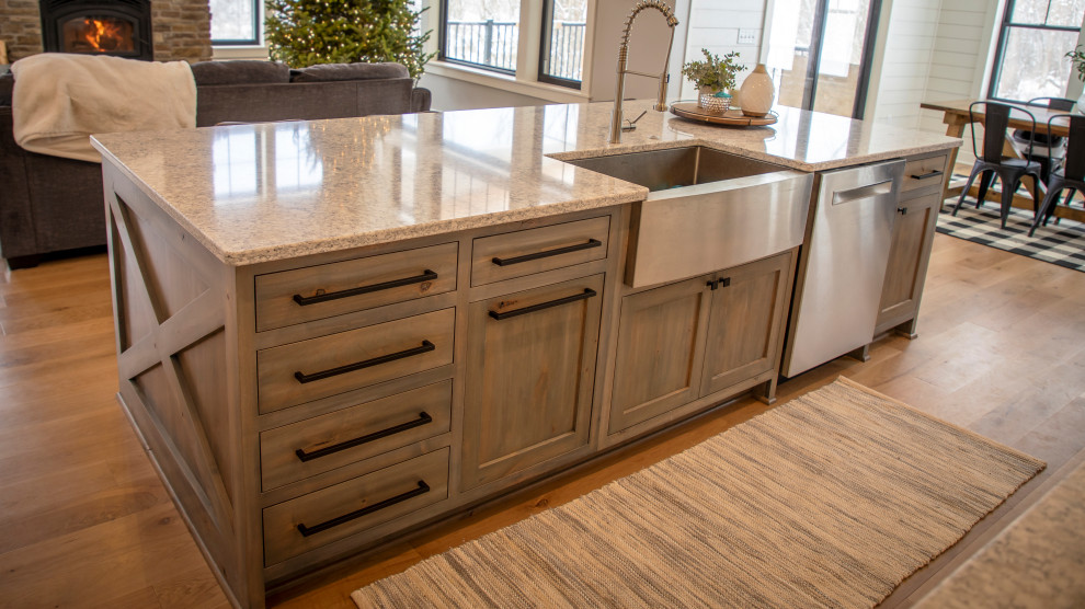 Inspiration for a mid-sized country l-shaped eat-in kitchen in Minneapolis with a farmhouse sink, shaker cabinets, grey cabinets, quartz benchtops, stainless steel appliances, medium hardwood floors, with island, brown floor and grey benchtop.
