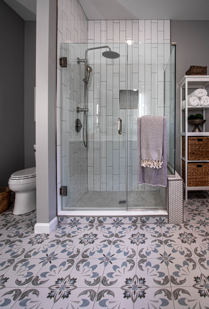 Источник вдохновения для домашнего уюта: главная ванная комната среднего размера в морском стиле с фасадами с выступающей филенкой, отдельно стоящей ванной, душем в нише, раздельным унитазом, белой плиткой, керамической плиткой, серыми стенами, полом из керамической плитки, врезной раковиной, столешницей из гранита, синим полом, душем с распашными дверями, белой столешницей, нишей, тумбой под две раковины и встроенной тумбой