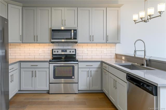 Open concept kitchen - mid-sized transitional u-shaped vinyl floor and brown floor open concept kitchen idea with an undermount sink, gray cabinets, quartzite countertops, stainless steel appliances, a peninsula and gray countertops