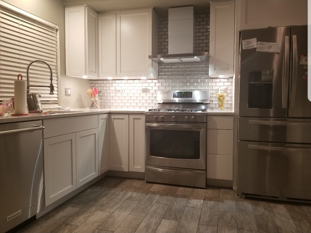 Design ideas for a mid-sized modern l-shaped eat-in kitchen in Los Angeles with an undermount sink, shaker cabinets, white cabinets, quartz benchtops, metallic splashback, glass tile splashback, stainless steel appliances, terrazzo floors, with island, multi-coloured floor and white benchtop.