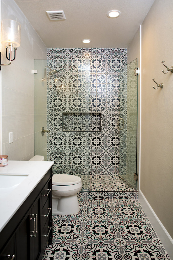 This is an example of a medium sized retro shower room bathroom in Las Vegas with raised-panel cabinets, black cabinets, a walk-in shower, a two-piece toilet, black and white tiles, ceramic tiles, white walls, ceramic flooring, a submerged sink, engineered stone worktops, multi-coloured floors, a hinged door, white worktops, a wall niche, a single sink and a freestanding vanity unit.