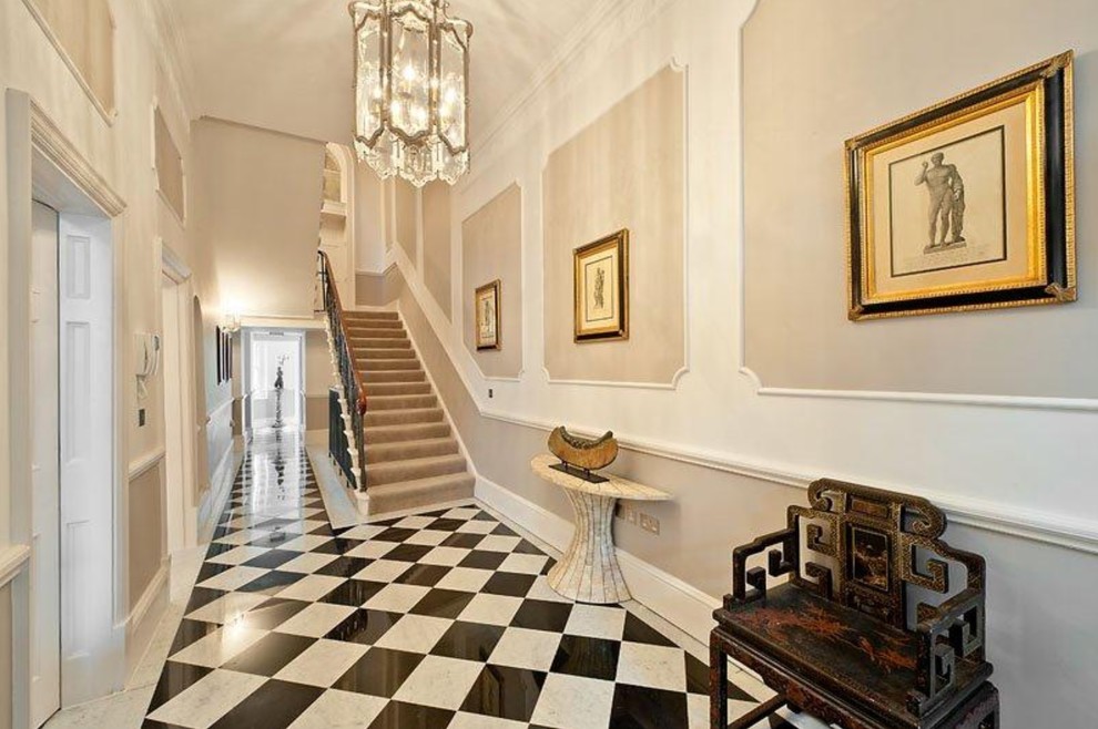 Expansive transitional entry hall in London with multi-coloured floor and beige walls.