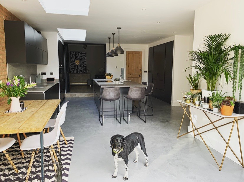 Design ideas for a mid-sized contemporary u-shaped open plan kitchen in Berkshire with a drop-in sink, flat-panel cabinets, black cabinets, tile benchtops, grey splashback, ceramic splashback, black appliances, concrete floors, with island, grey floor, grey benchtop and coffered.