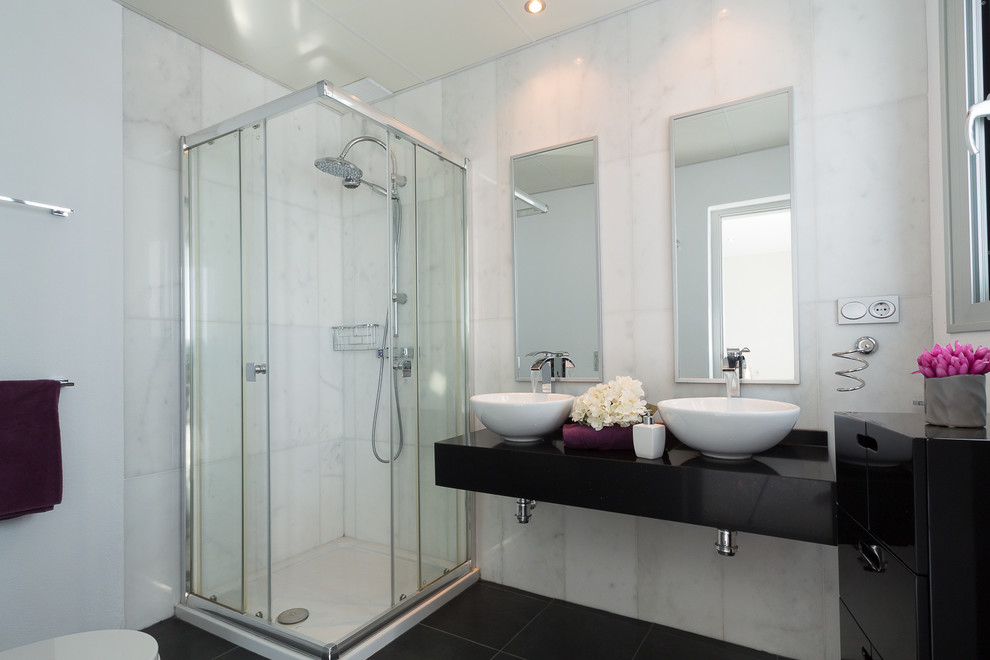 Inspiration for a mid-sized contemporary 3/4 bathroom in Other with open cabinets, a corner shower, a one-piece toilet, white tile, ceramic tile, white walls, ceramic floors, a vessel sink, marble benchtops, black floor and a sliding shower screen.