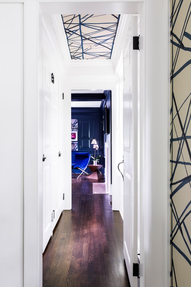 Photo of a mid-sized transitional hallway in New York with white walls, dark hardwood floors and brown floor.