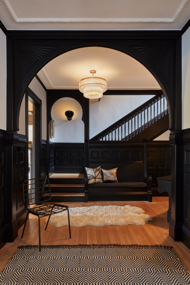 This is an example of a mid-sized traditional foyer in Boston with black walls, brown floor, medium hardwood floors and decorative wall panelling.