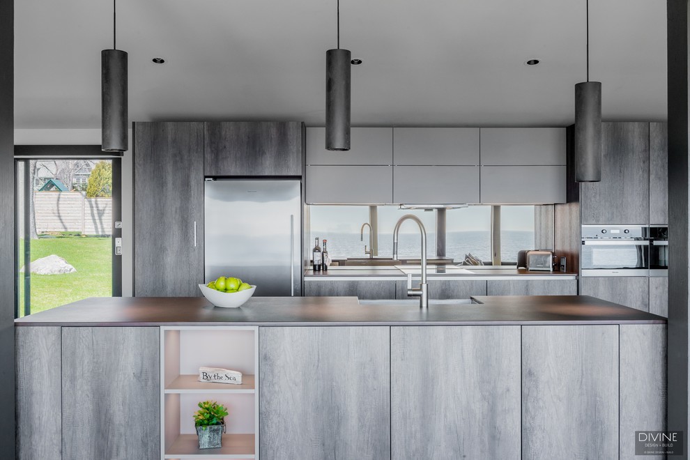Large eclectic single-wall open plan kitchen in Boston with a farmhouse sink, flat-panel cabinets, dark wood cabinets, granite benchtops, metallic splashback, glass sheet splashback, stainless steel appliances, slate floors, with island, grey floor and brown benchtop.