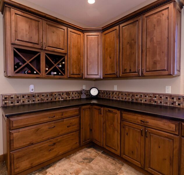 This is an example of a large country u-shaped utility room in Denver with a drop-in sink, raised-panel cabinets, medium wood cabinets, granite benchtops, beige walls, slate floors and a side-by-side washer and dryer.