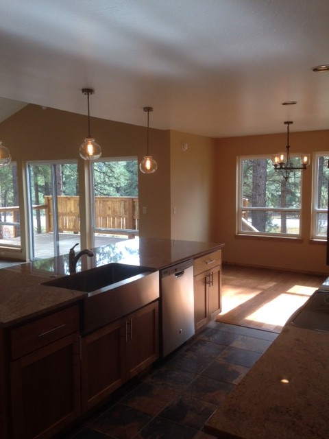 Inspiration for a mid-sized transitional single-wall medium tone wood floor open concept kitchen remodel in Albuquerque with a farmhouse sink, shaker cabinets, medium tone wood cabinets, granite countertops, gray backsplash, subway tile backsplash, stainless steel appliances and an island