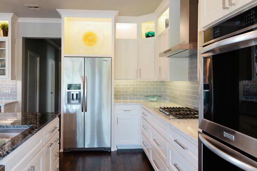 Mid-sized beach style u-shaped dark wood floor eat-in kitchen photo with an undermount sink, shaker cabinets, white cabinets, granite countertops, gray backsplash, glass tile backsplash, stainless steel appliances and an island