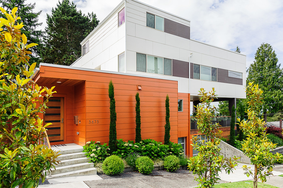 This is an example of a mid-sized contemporary three-storey orange house exterior in Seattle with a flat roof.