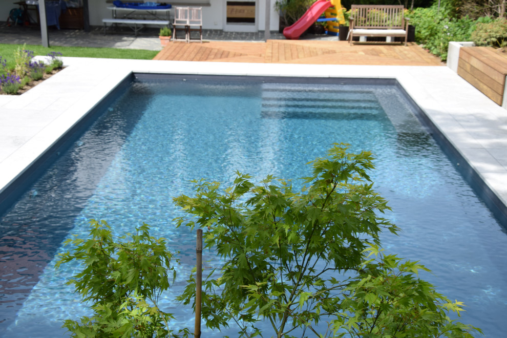 Design ideas for a large mediterranean side yard rectangular pool in Frankfurt with natural stone pavers.
