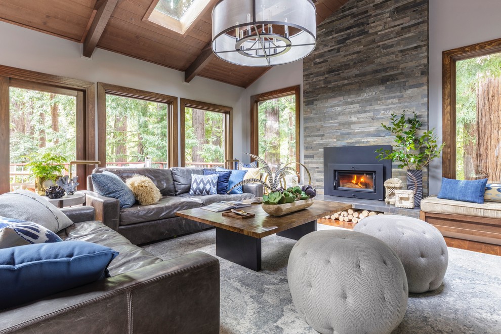 Mid-sized eclectic open concept family room in San Francisco with grey walls, medium hardwood floors, a standard fireplace, a stone fireplace surround, a wall-mounted tv and brown floor.