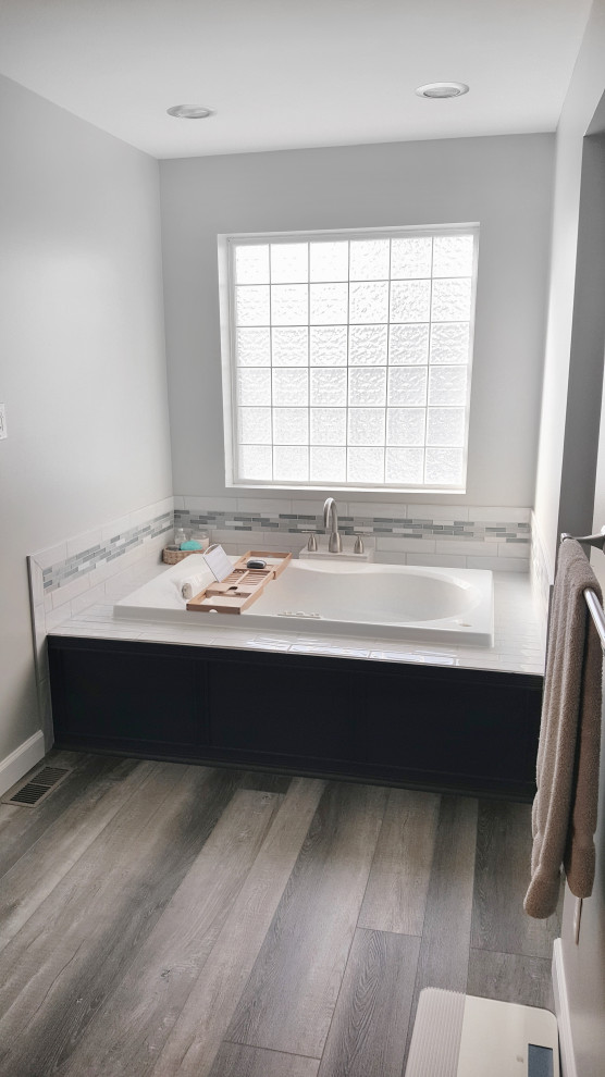 Mid-sized modern master bathroom in Other with blue cabinets, a drop-in tub, blue tile, glass tile, white walls, onyx benchtops, brown floor, beige benchtops, a single vanity and a built-in vanity.