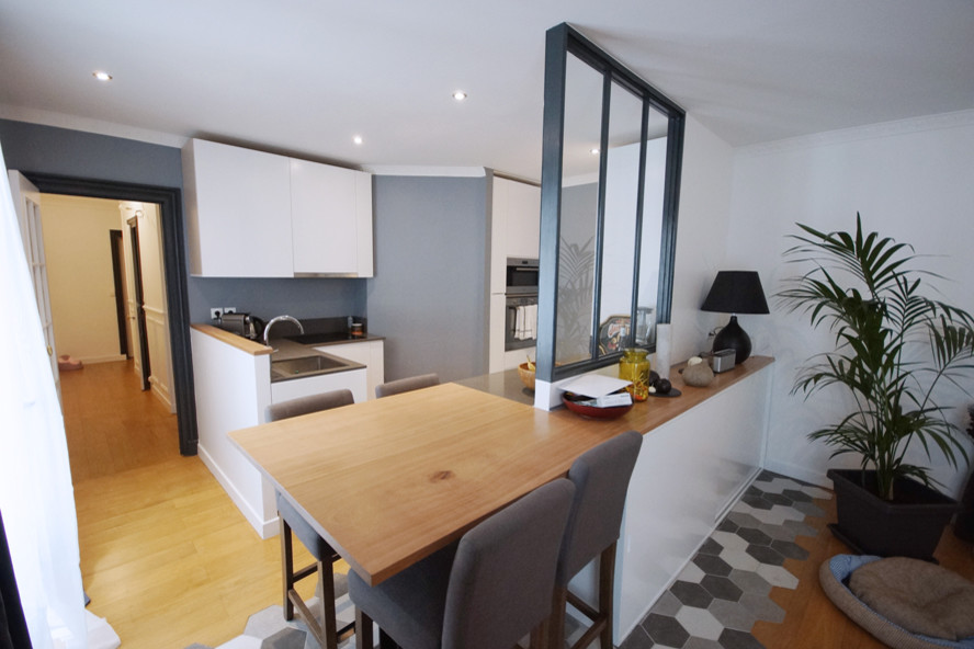 Mid-sized contemporary galley open plan kitchen in Paris with light hardwood floors, an undermount sink, beaded inset cabinets, white cabinets, wood benchtops, grey splashback, stone slab splashback, panelled appliances and with island.