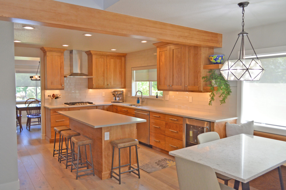 Inspiration for a mid-sized transitional u-shaped eat-in kitchen in Denver with an undermount sink, shaker cabinets, medium wood cabinets, quartz benchtops, white splashback, glass tile splashback, stainless steel appliances, light hardwood floors, with island, grey floor, multi-coloured benchtop and exposed beam.